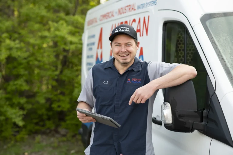 American Aqua employee holding a tablet leaning against a white service fan