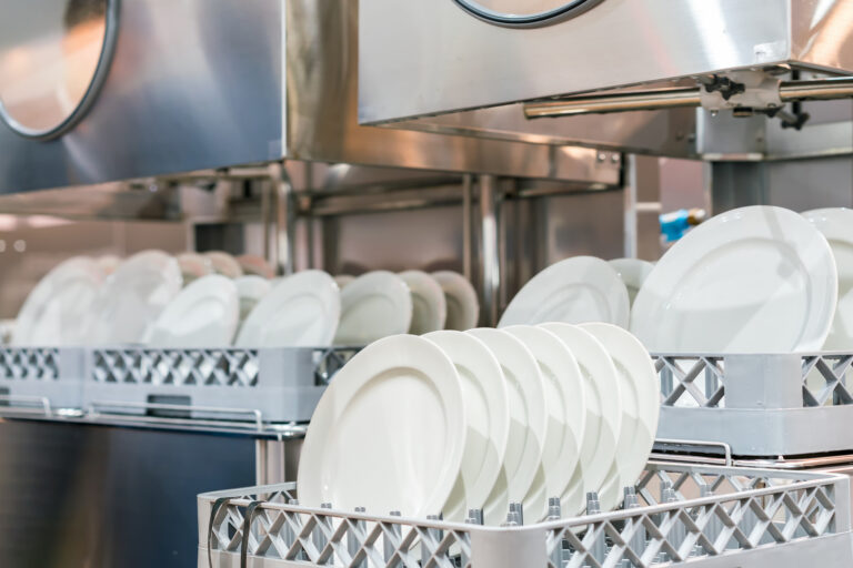 many dish or white plate arranged on basket for cleaning by automatic dishwasher machine in kitchen room restaurant