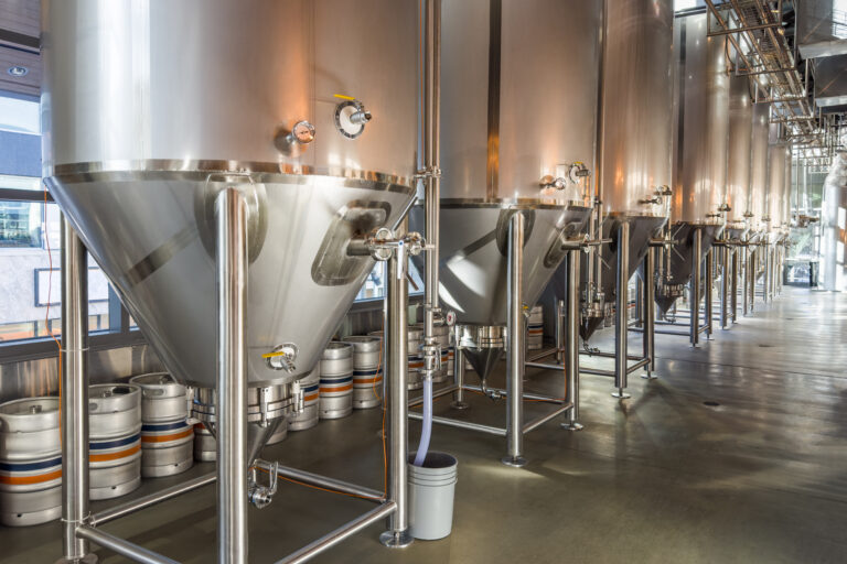 Modern beer factory, row of steel tanks for beer fermentation and maturation.